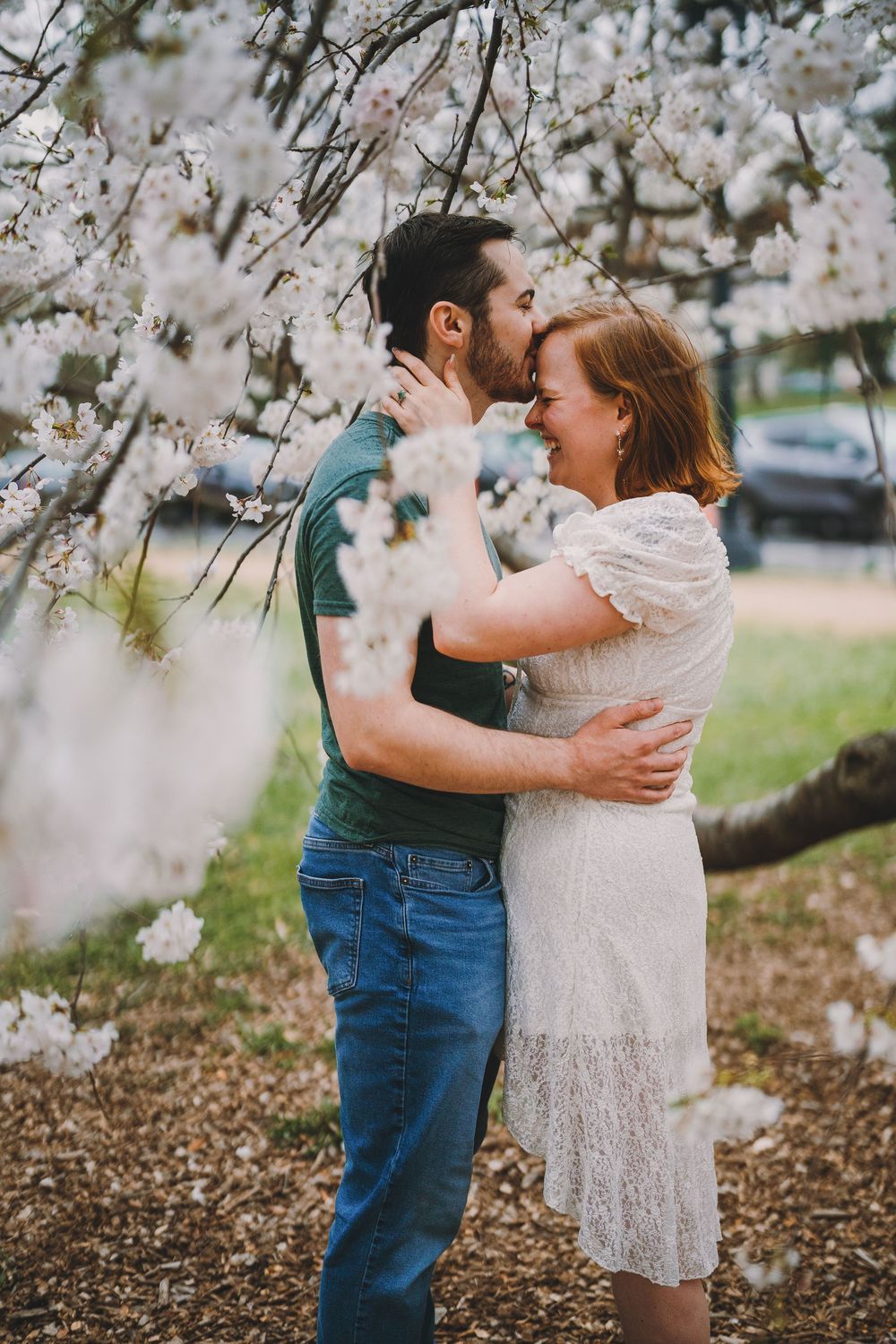 Zach and Clarissa embrace in the cherry blossoms at their engagement session at the Tidal Basin.