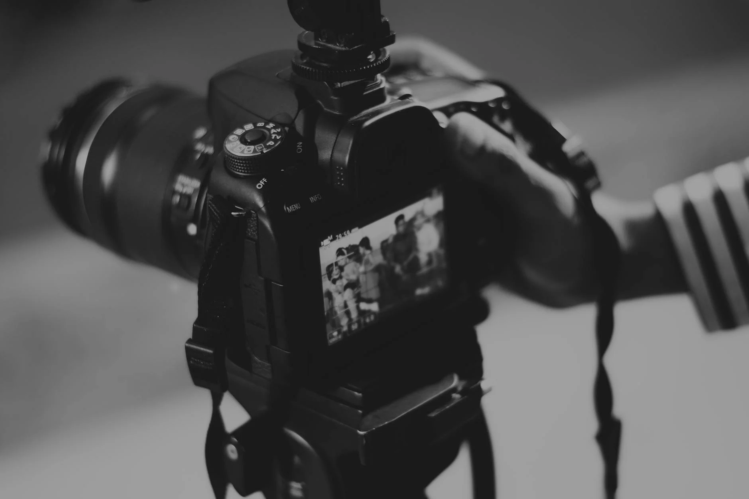 Close-up shot of a DSLR camera with a telephoto lens mounted against a blurred background.