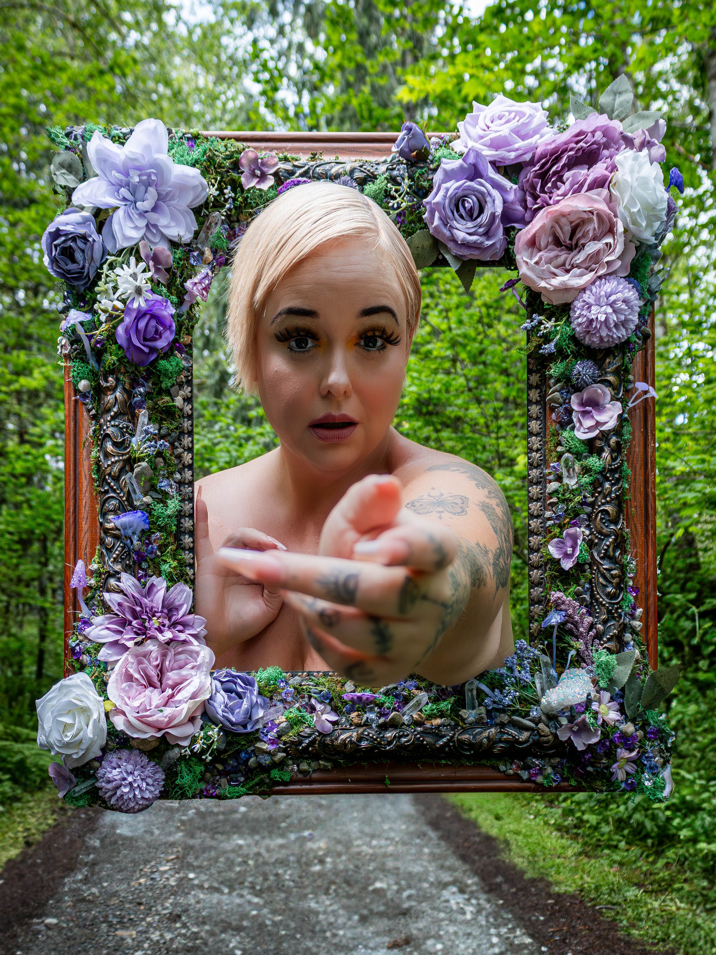 An ornate wooden frame decorated with purple roses and flowers creates a striking outdoor portrait composition.