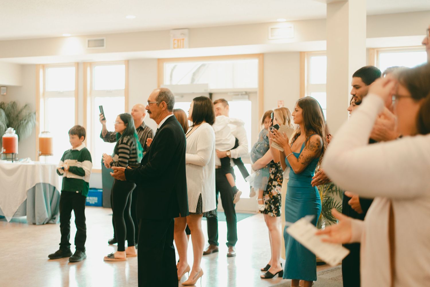 Family and friends watch as bride and groom enter lunch time wedding reception