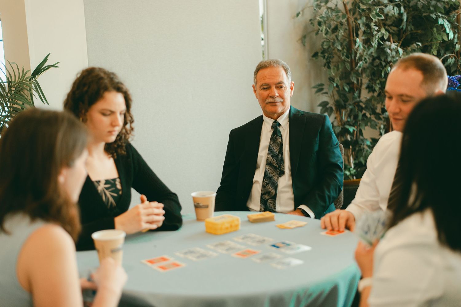 Family and friends laugh and talk and play games together at lunchtime wedding reception