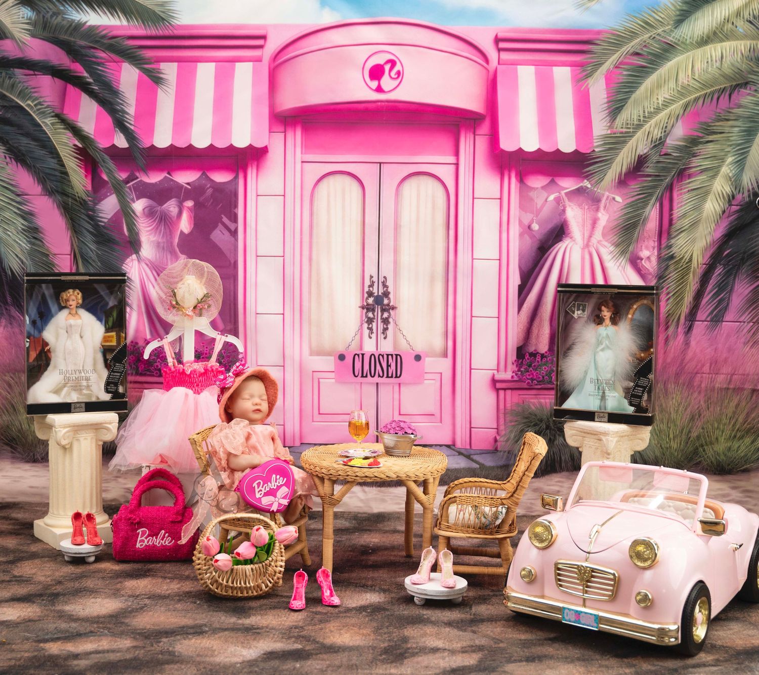 Pink Barbie-themed storefront with princess dresses, a convertible car, and decorative palm trees.