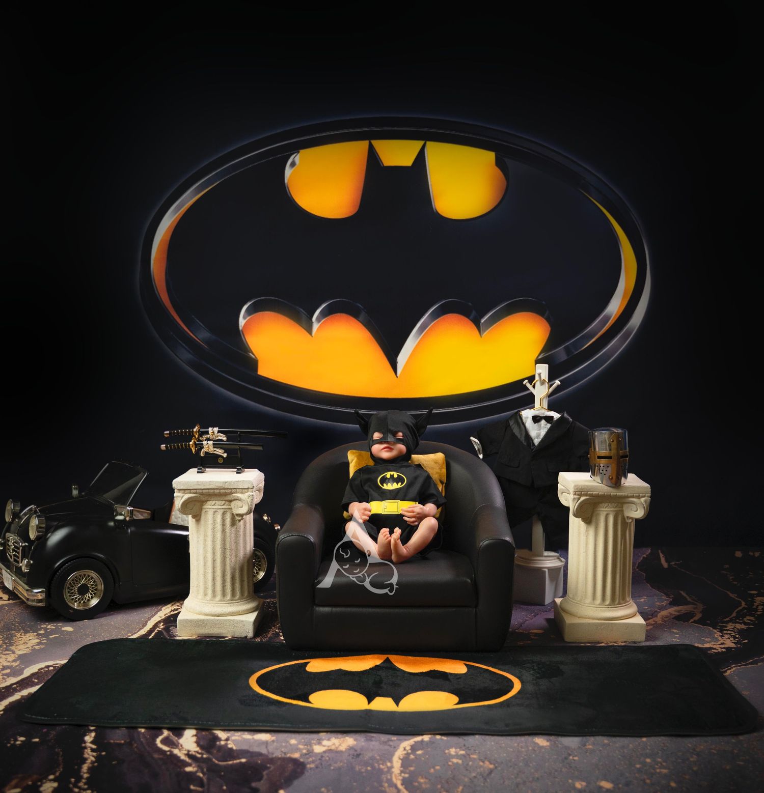 Batman-themed photo setup with iconic bat symbol logo illuminated against dark background with decorative columns.