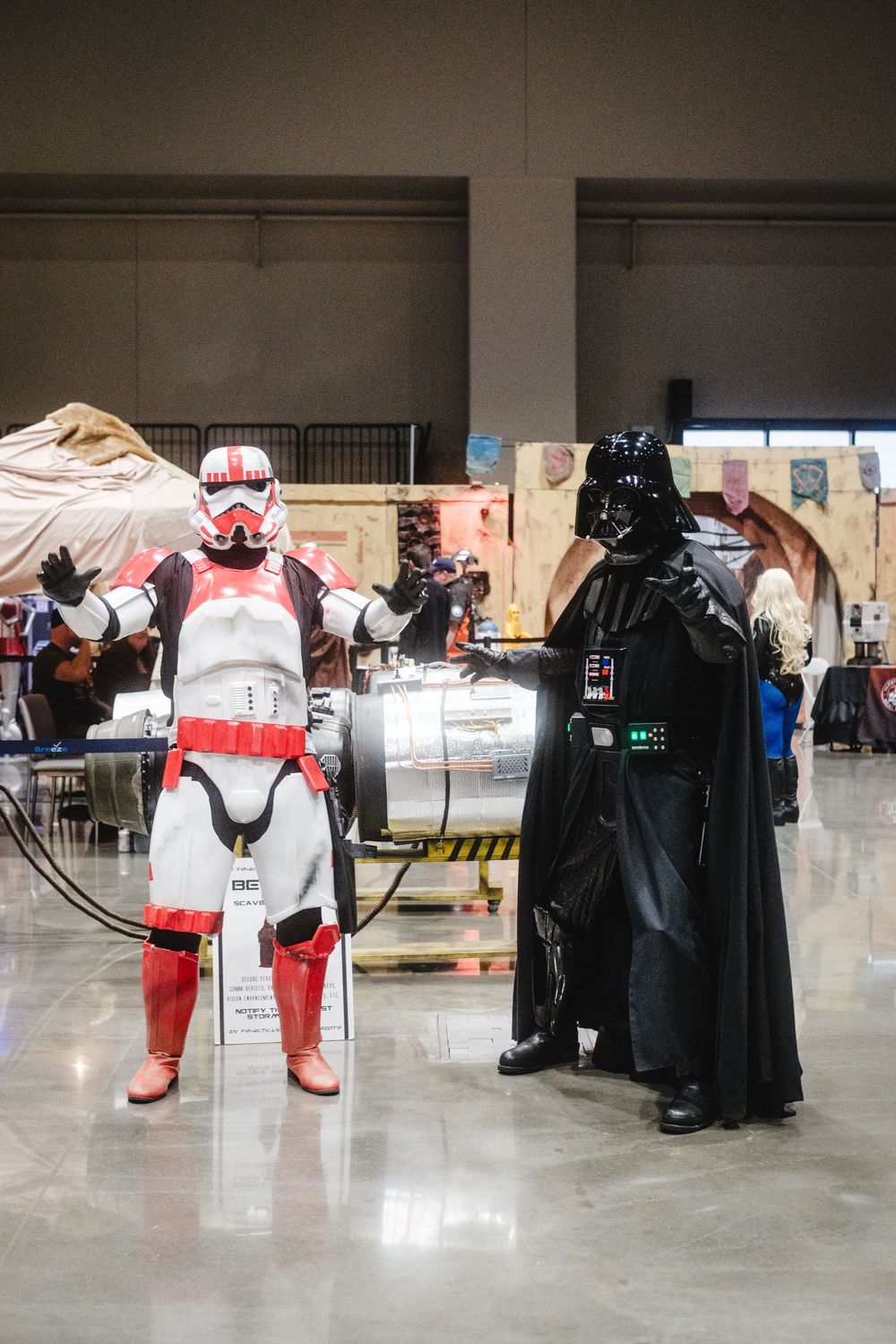 Cosplayers dressed as Star Wars characters Darth Vader and a Stormtrooper pose together at a convention.