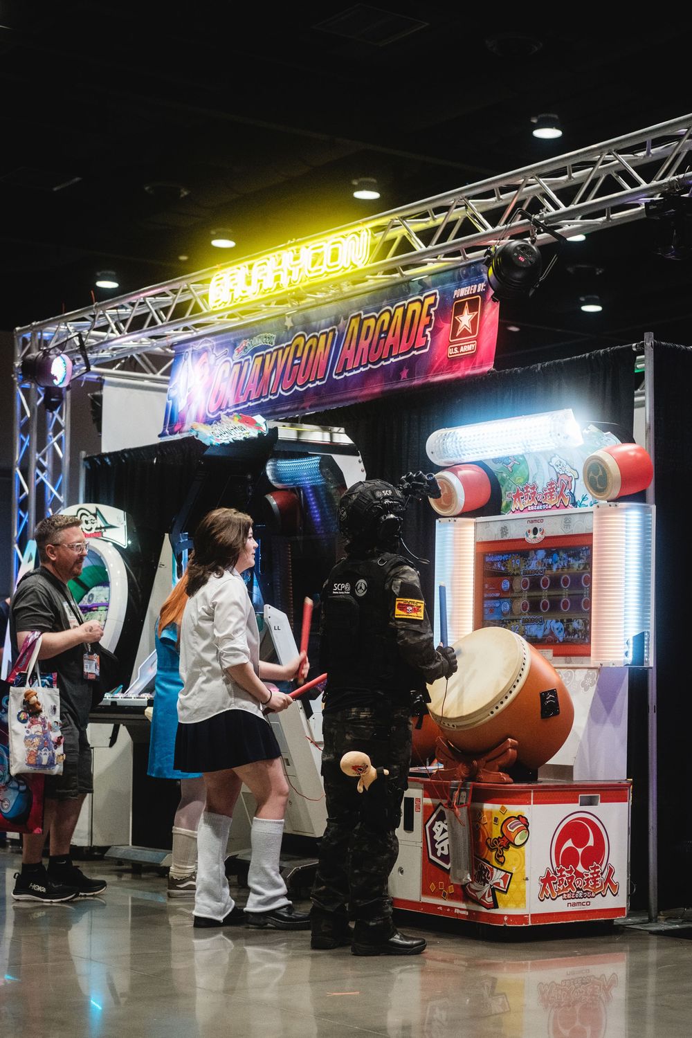 Arcade game setup with colorful lighting and equipment at a gaming convention or entertainment venue.