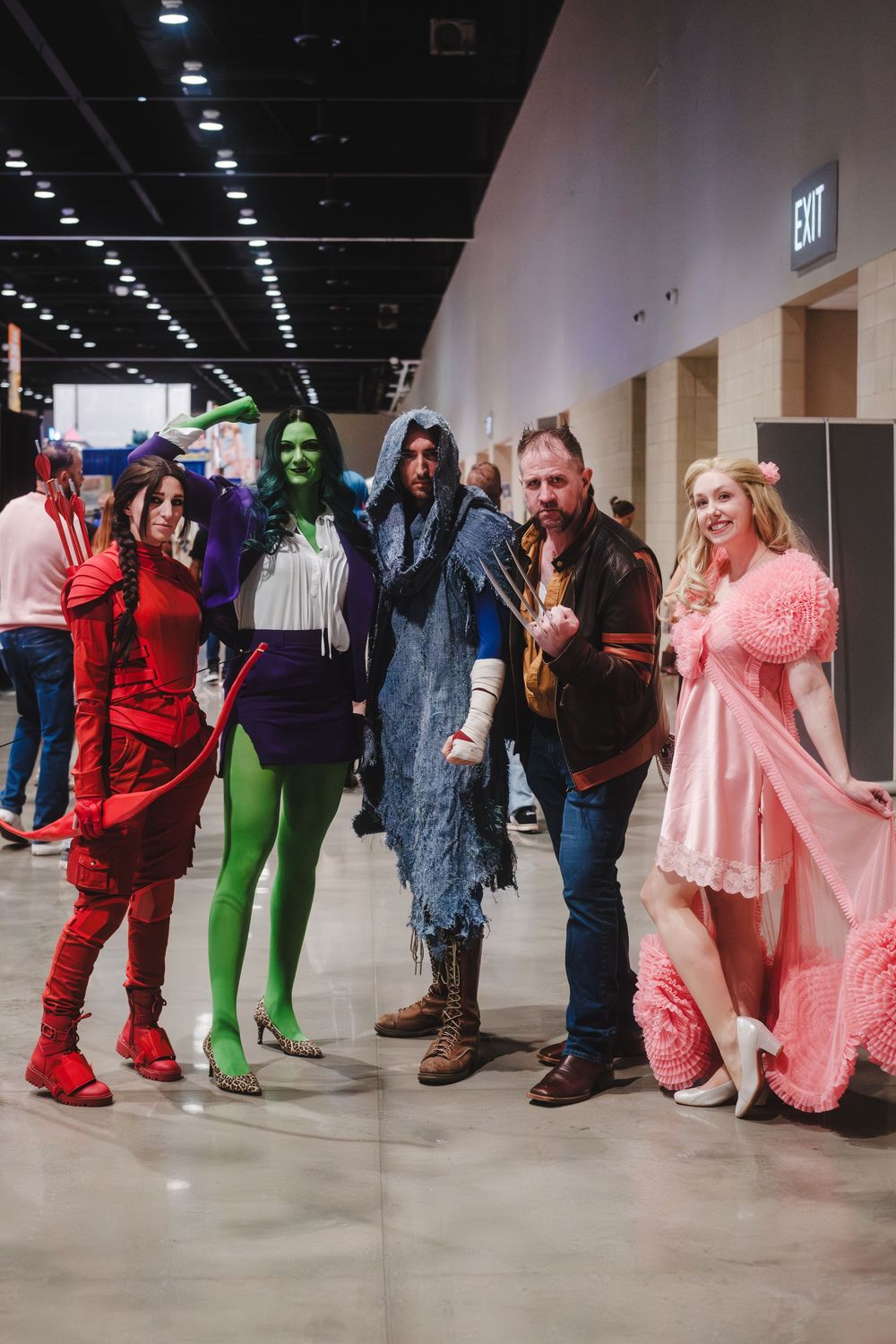 A group of cosplayers dressed in various colorful costumes pose together at a convention center.