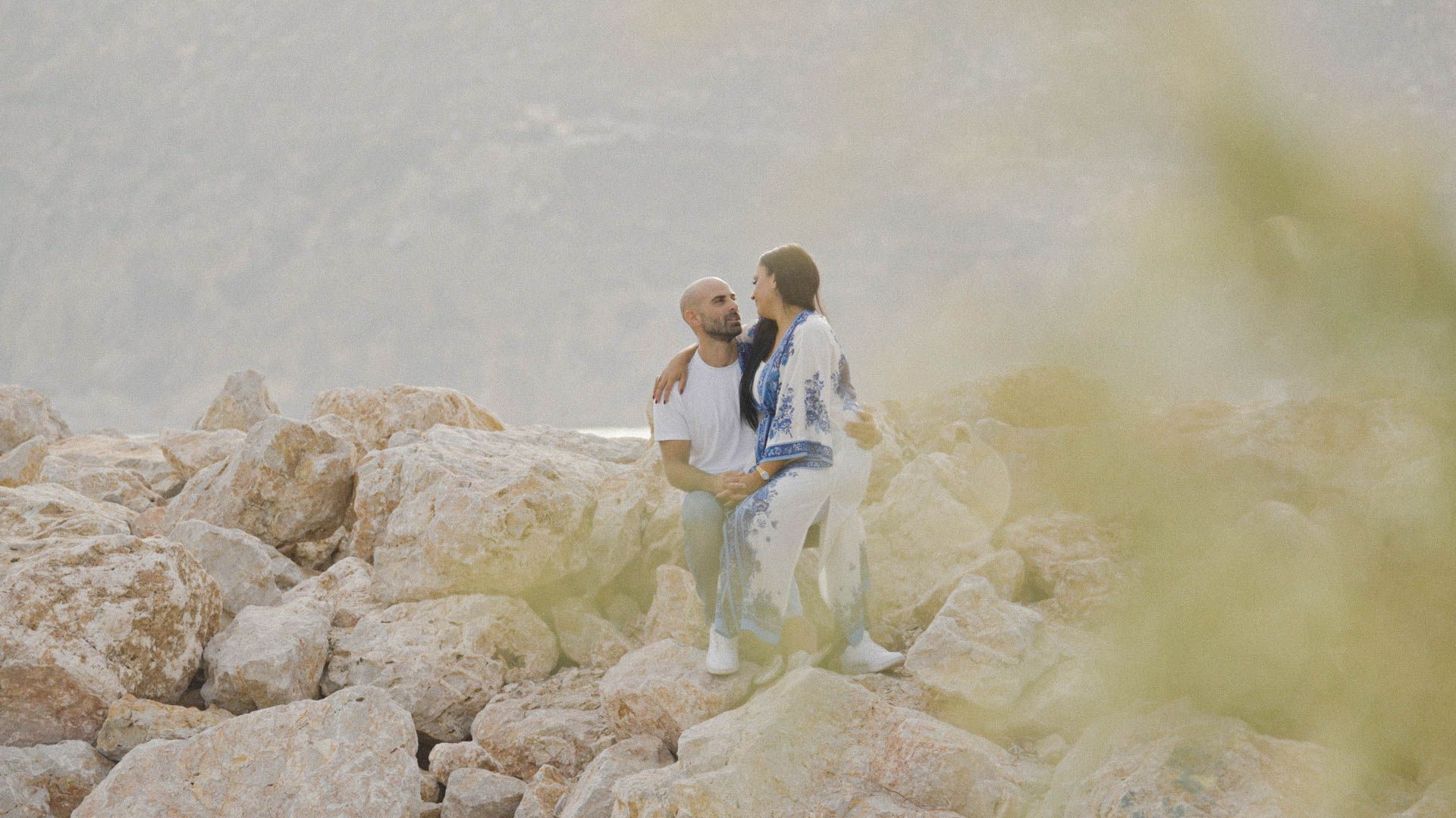A couple walking together on rocky terrain during a misty outdoor adventure.