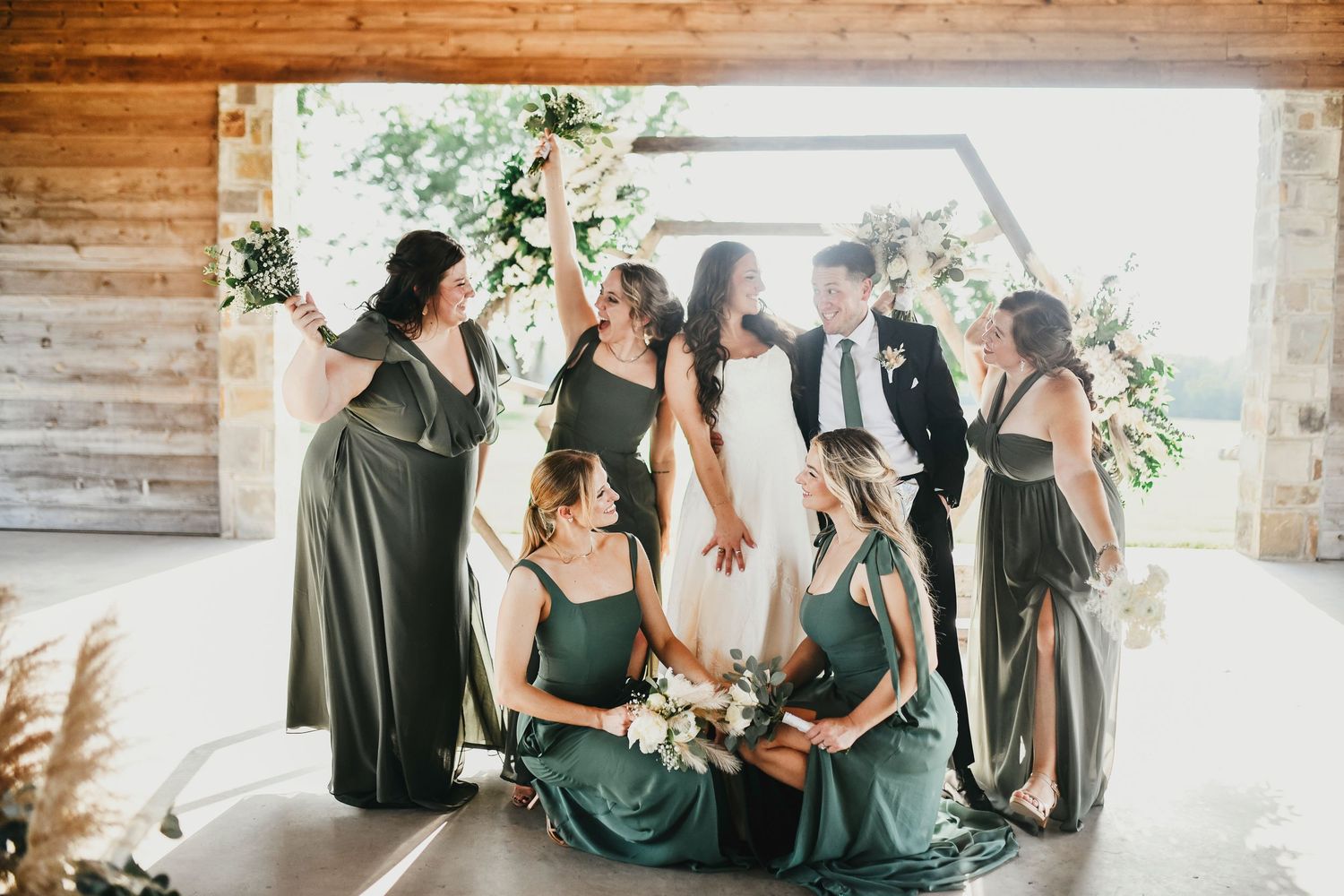 High-energy wedding party cheering with arms raised at The Madelyn