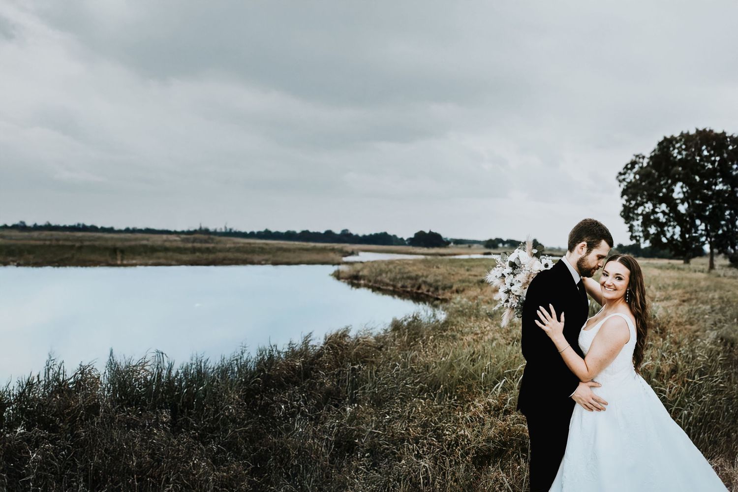 gorgeous wedding photo of a bride and groom standing in a field before a storm at their rustic collinsville wedding venue