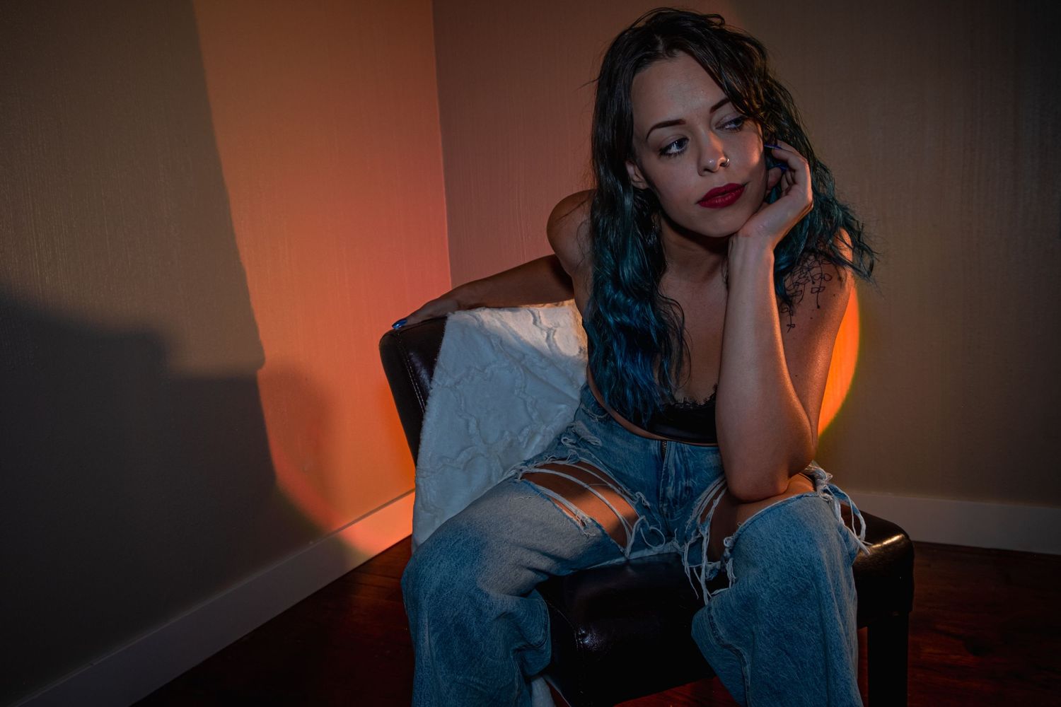 Moody portrait in jeans against orange-lit wall.