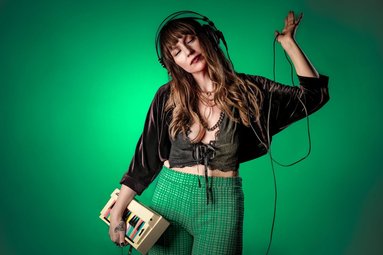 Fashion portrait with green background featuring model with headphones and vintage player.