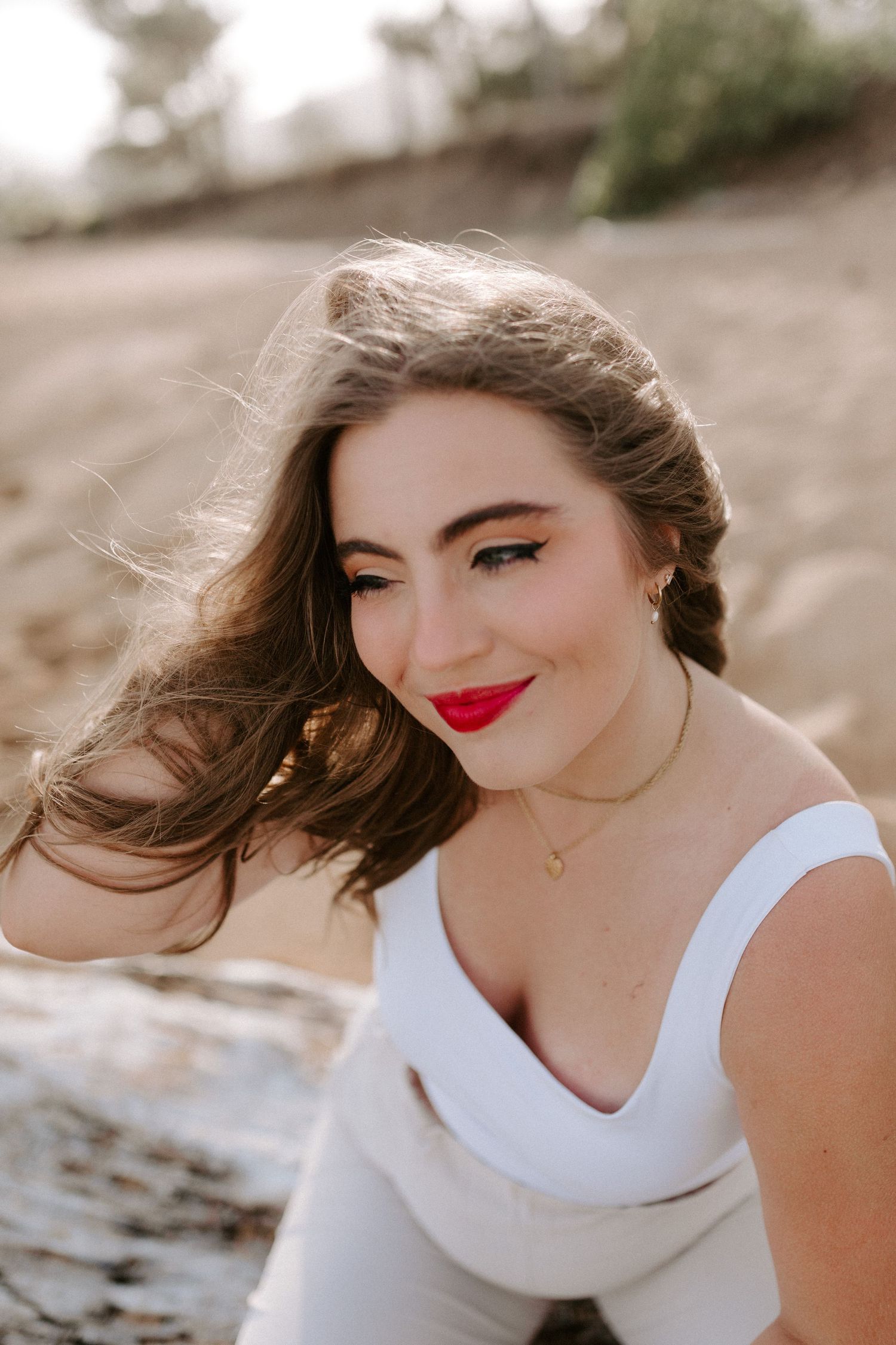 A portrait of someone in white beachwear with wind-swept hair against a natural backdrop.