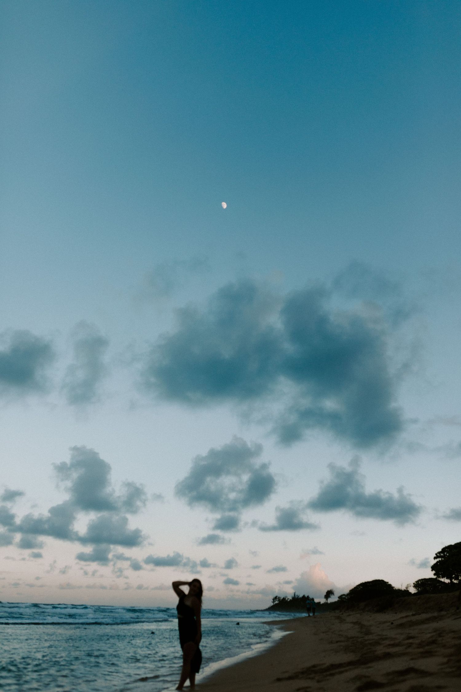 Silhouette of a person standing on beach during sunset with dramatic cloudy sky.