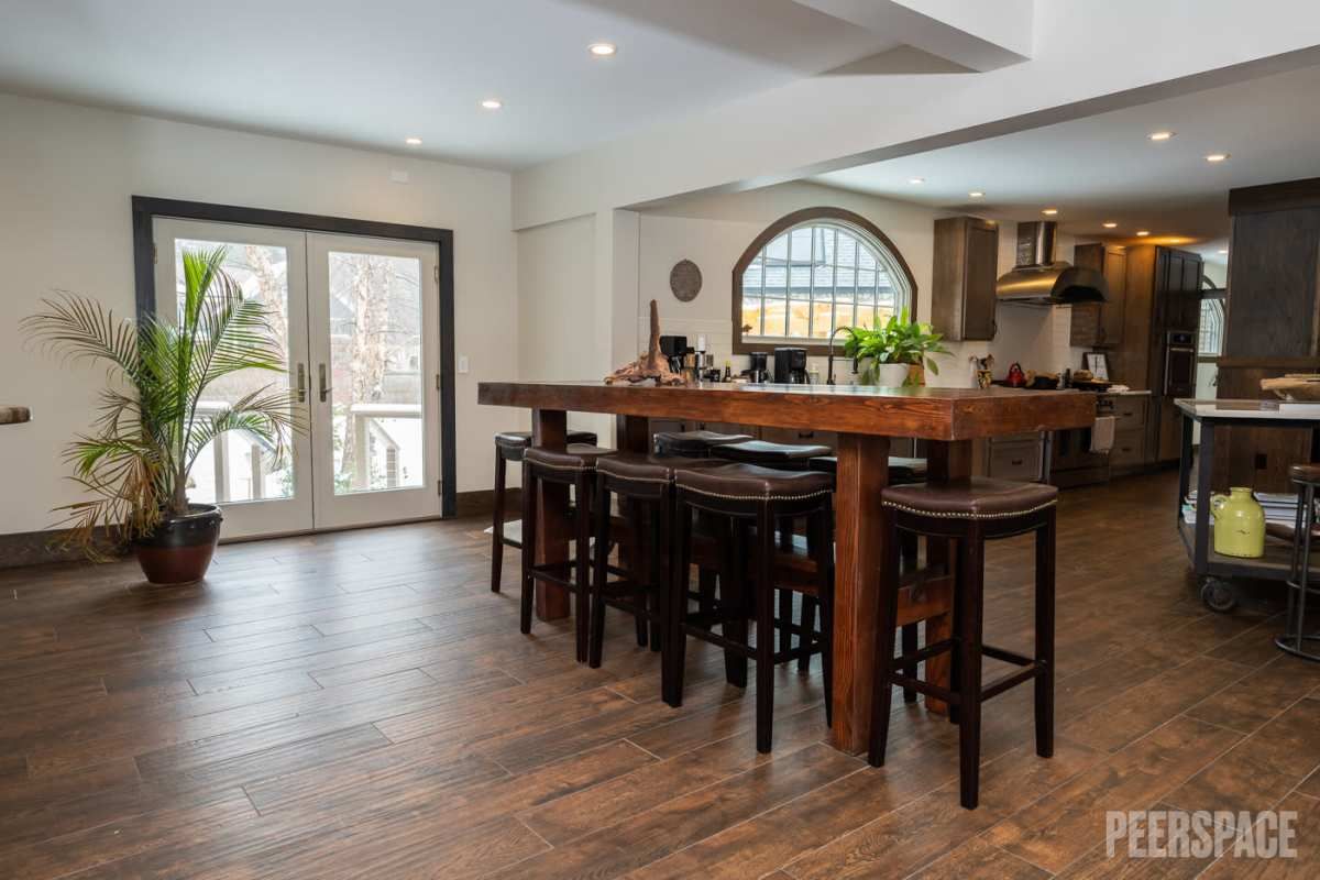 Open concept dining area with wood floors, bar seating, and arched window connecting to modern kitchen.