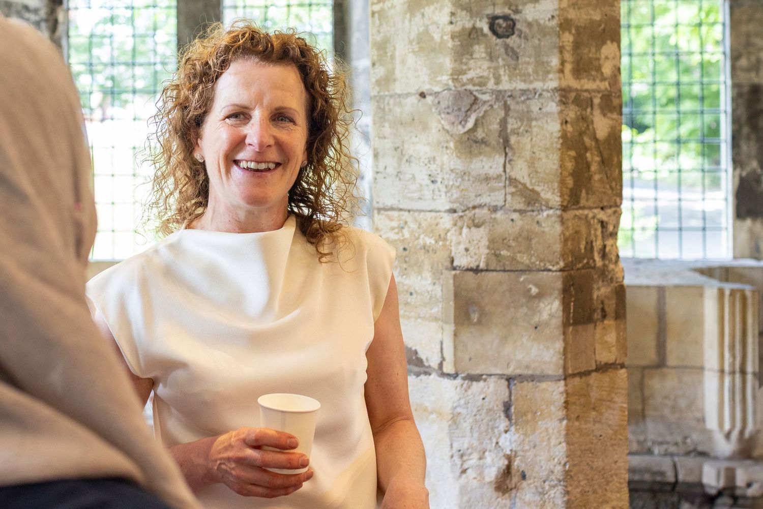 Corporate event photography for York Civic Trust. A person at York Hospitium in a sleeveless white top next to a stone pillar.