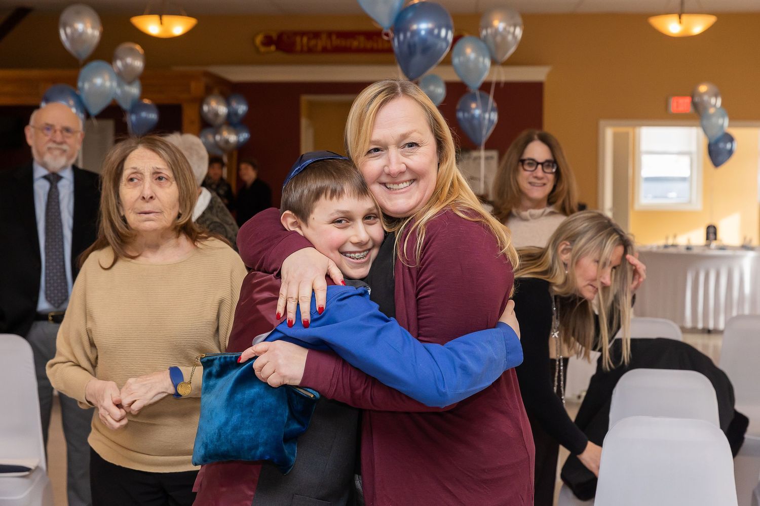 A casual group photo at an event with blue and silver balloons decorating the background.