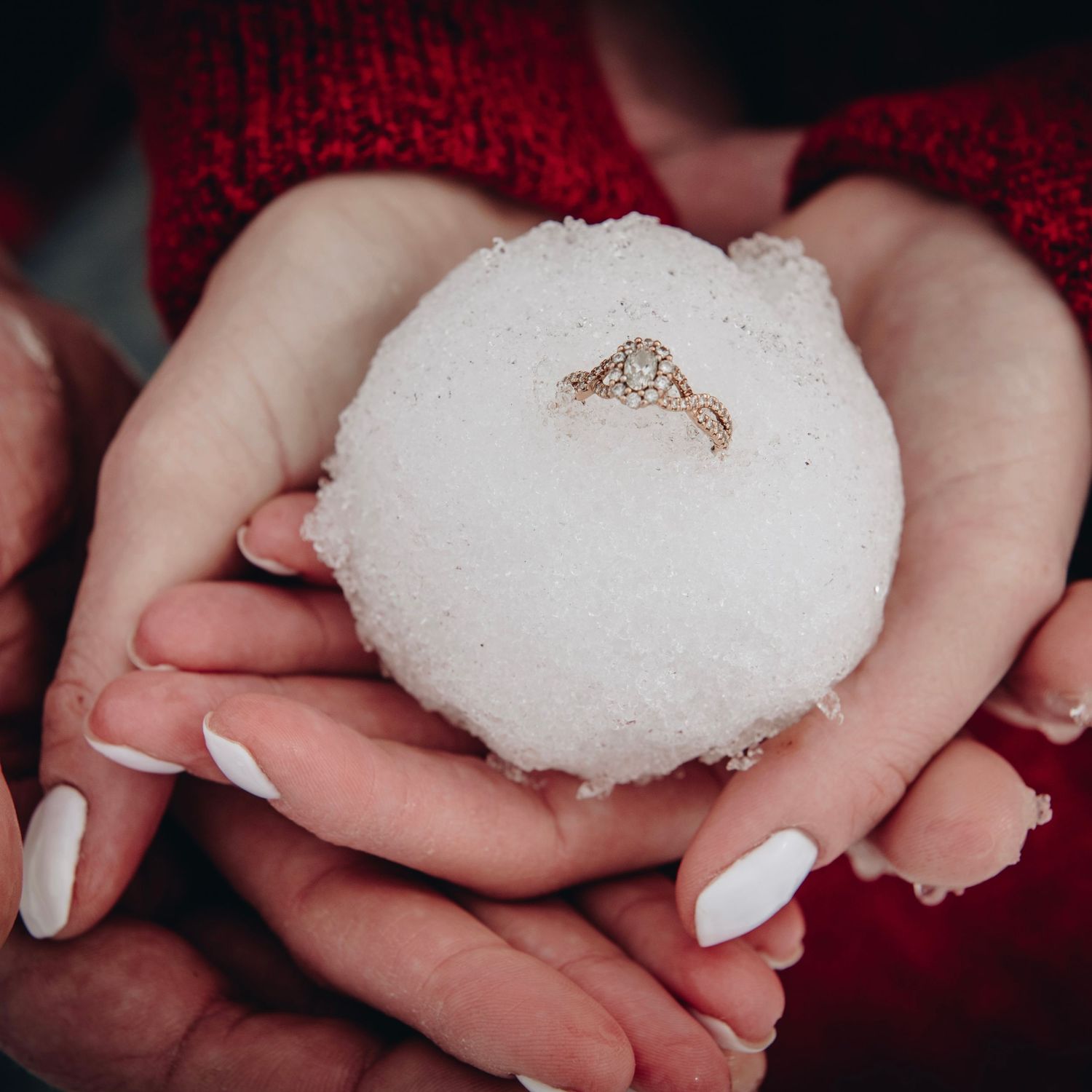 An engagement ring nestled in a perfectly round snowball held by manicured hands. Massachusetts Engagement Photographer- Affordable