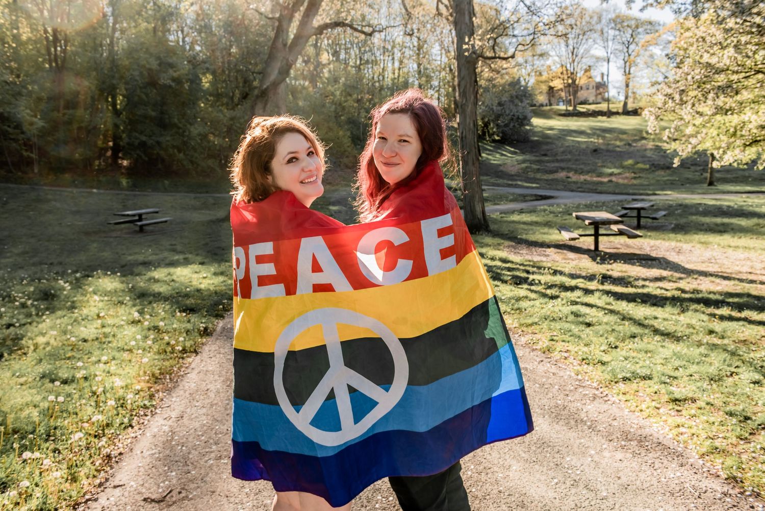 A couple holding a pride peace flag in a park setting. LGBT LGBTQ+ Friendly photographer