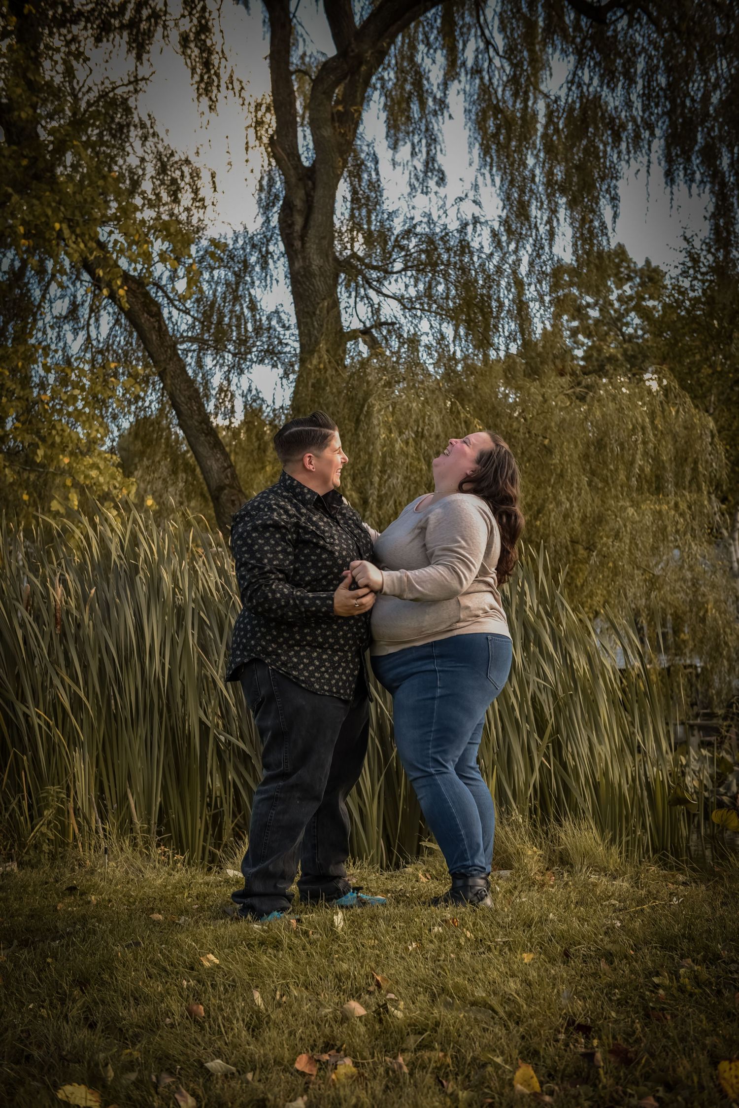 Couple sharing intimate moment among tall grass and willow trees at sunset. LGBT LGBTQ+ Friendly photographer