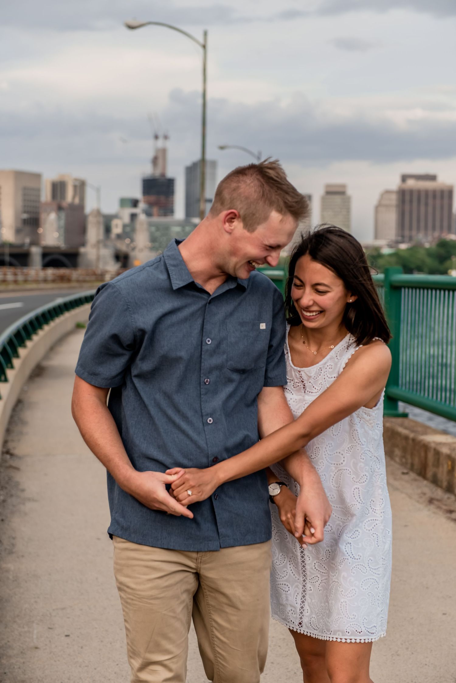 Sweet candid moment of couple laughing together on urban bridge. Massachusetts Engagement Photographer- Affordable