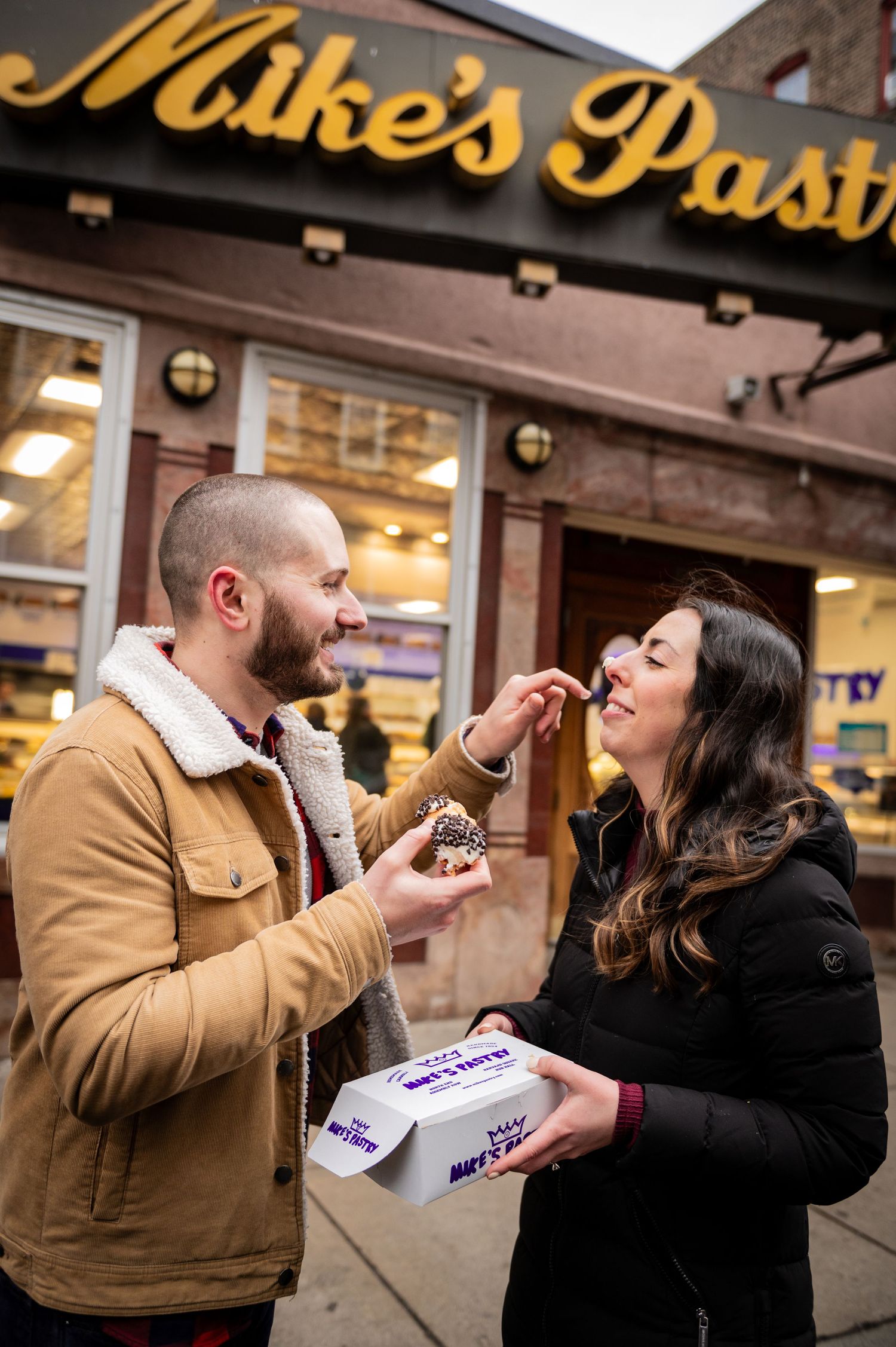 Sharing pastries outside Mike's Pastry shop in Boston's North End. Boston Engagement Photos- Affordable