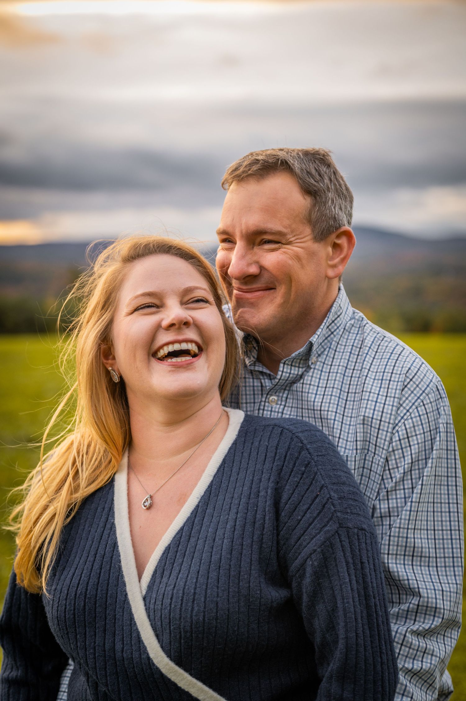 Golden hour portrait in rolling countryside with dramatic cloudy sky. New Hampshire Engagement Photos- Affordable