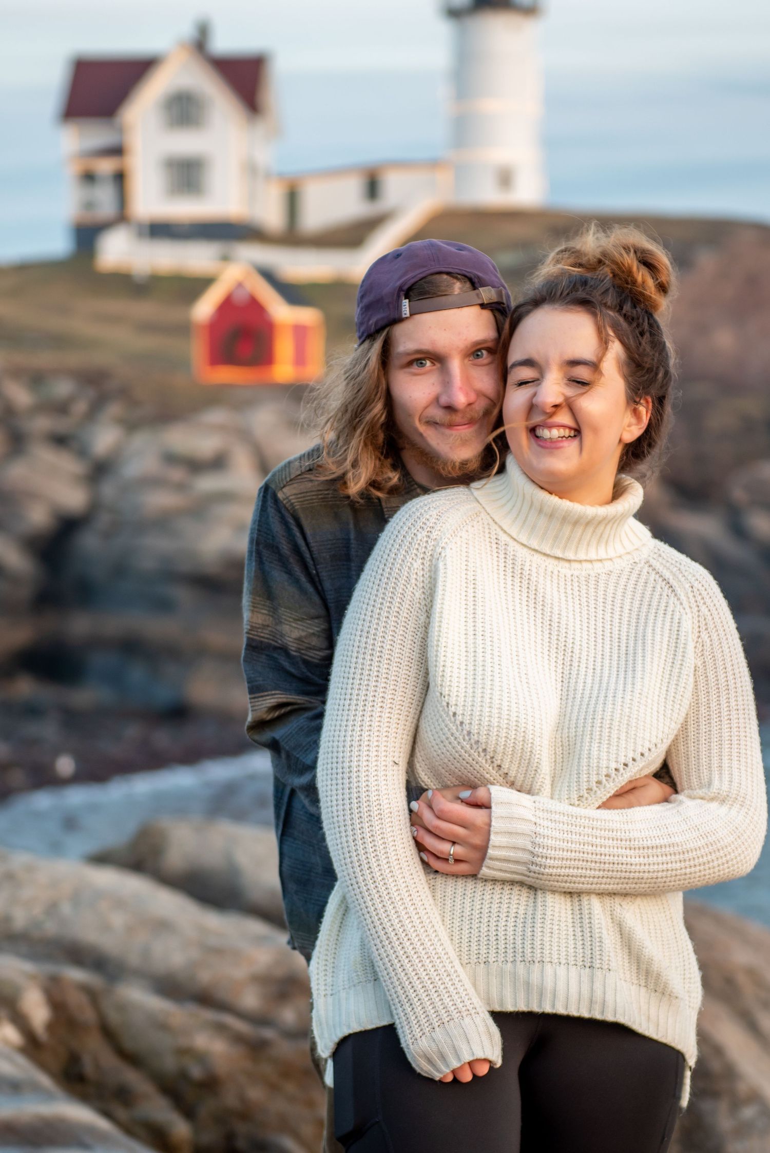 A couple embraces while standing by the Nubble Lighthouse in York, Maine.