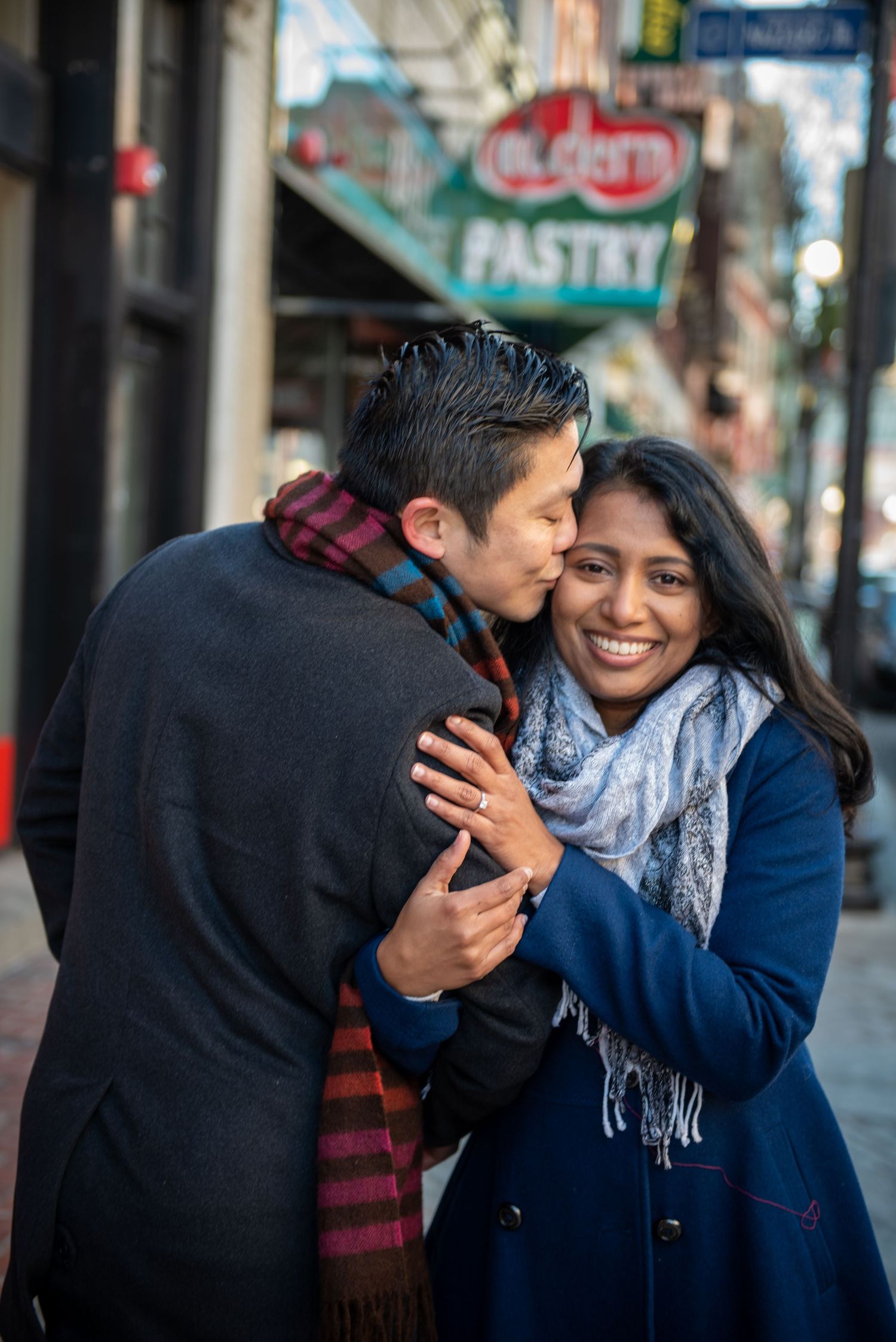 A tender moment shared between a couple outside a pastry shop. Massachusetts Engagement Photographer Serving New England