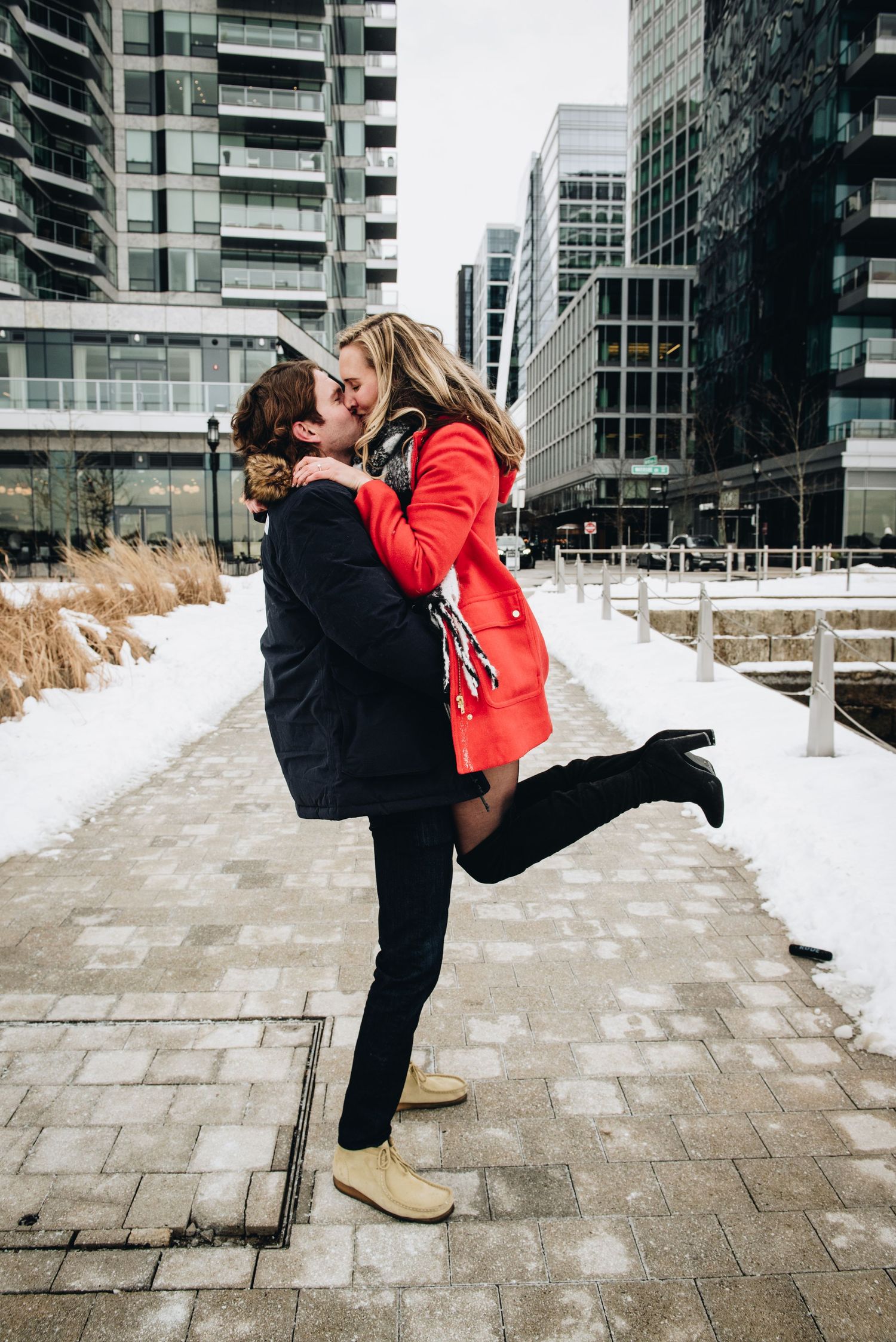 A romantic winter moment between a couple in front of modern city buildings. Massachusetts Engagement Photographer Serving New England