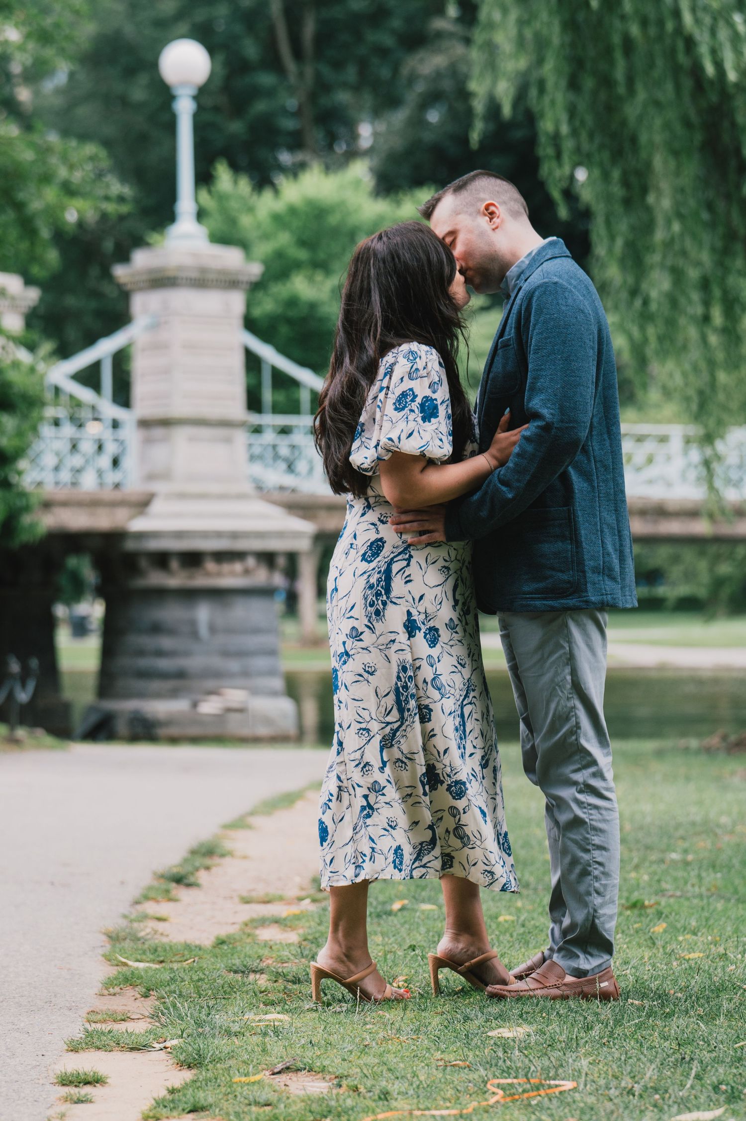 A couple sharing an intimate moment near a stone bridge in a park setting. Boston Engagement & Wedding Photographer