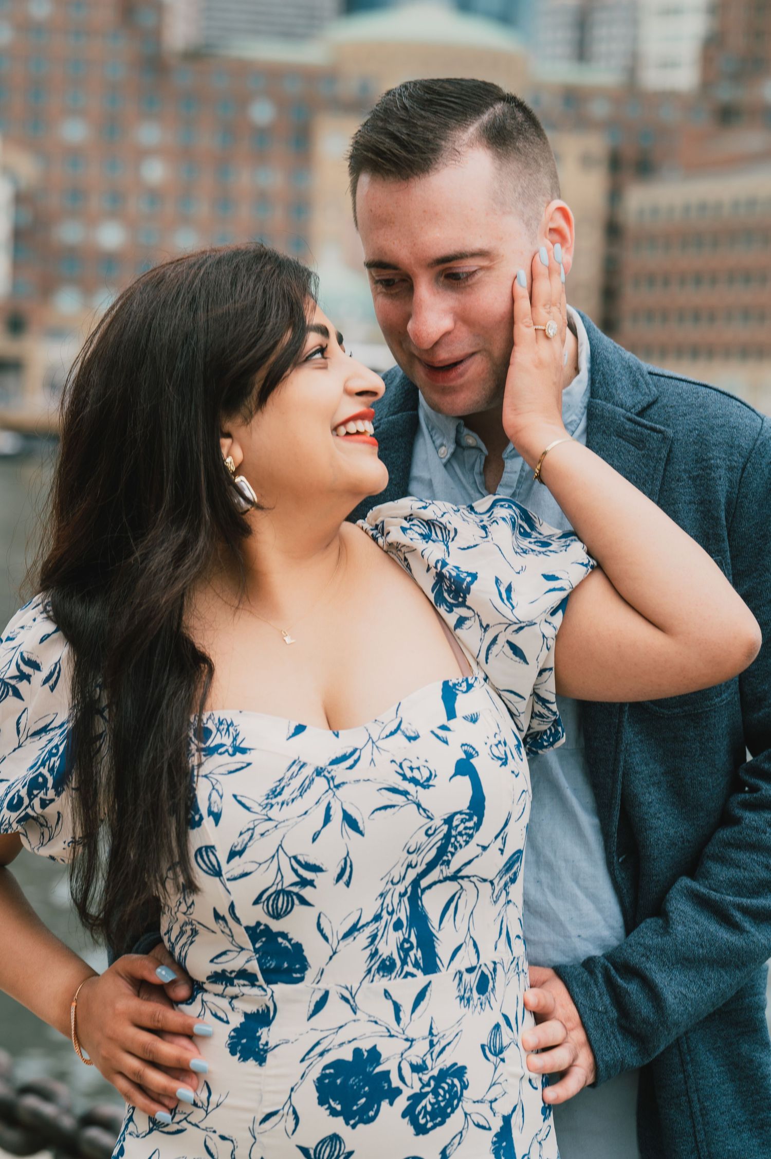 A romantic couple shares an intimate moment against a backdrop of Boston buildings. Boston Engagement & Wedding Photographer