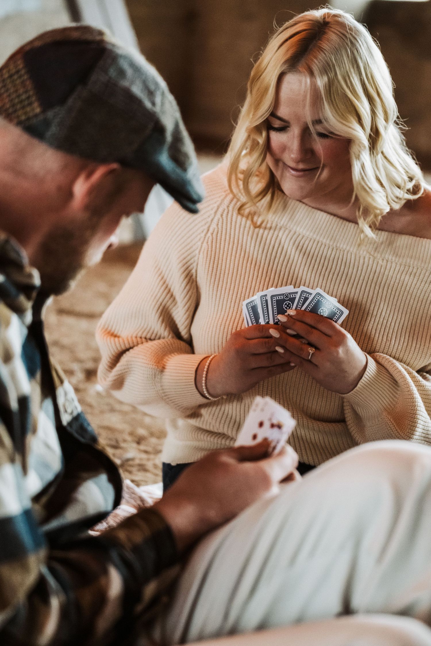 A couple engages in a friendly card game while relaxing together on a cozy indoor afternoon.