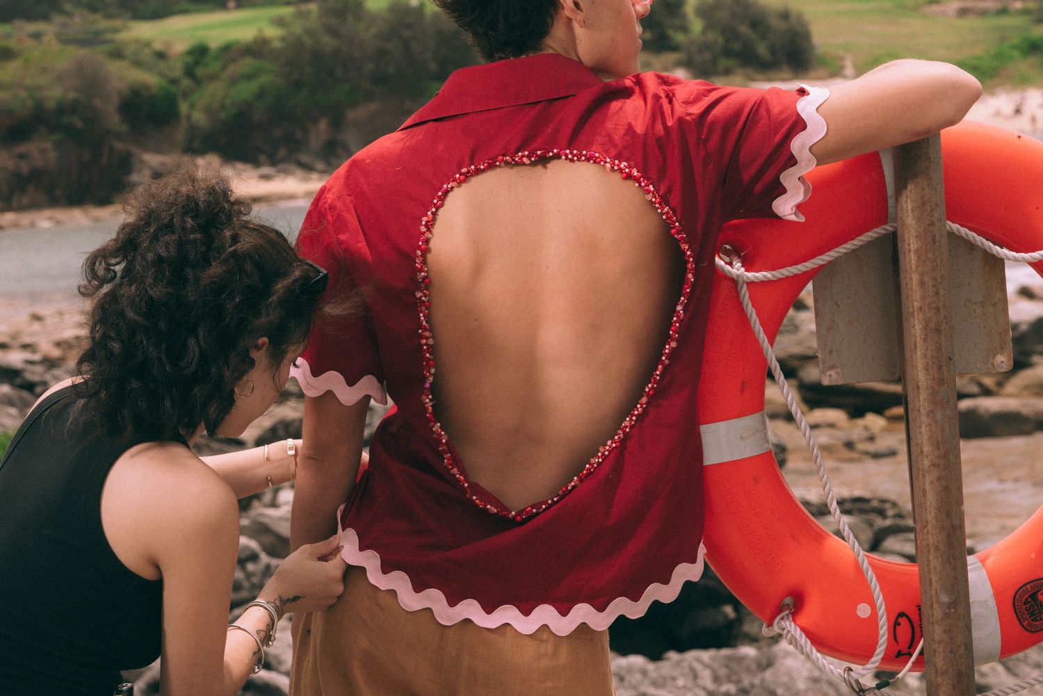 Fashion designer touching a vintage clothing piece in a look book photoshoot at the beach.