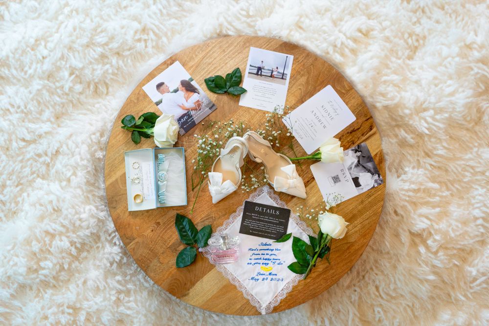 Wedding details arranged on a round wooden tray including floral elements and paper items.