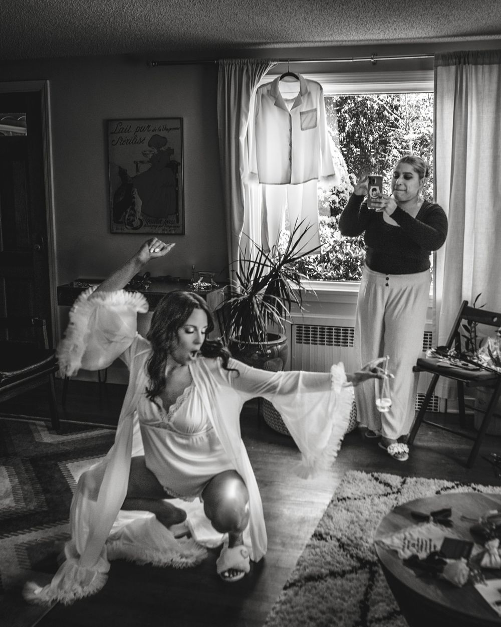 Black and white photo of wedding preparation moments in a cozy living room setting.