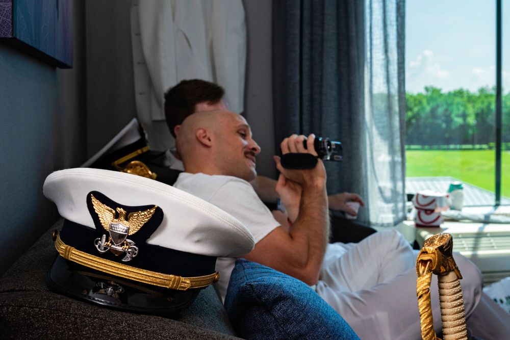 Someone wearing a naval captain's hat relaxes on a couch with a drink.