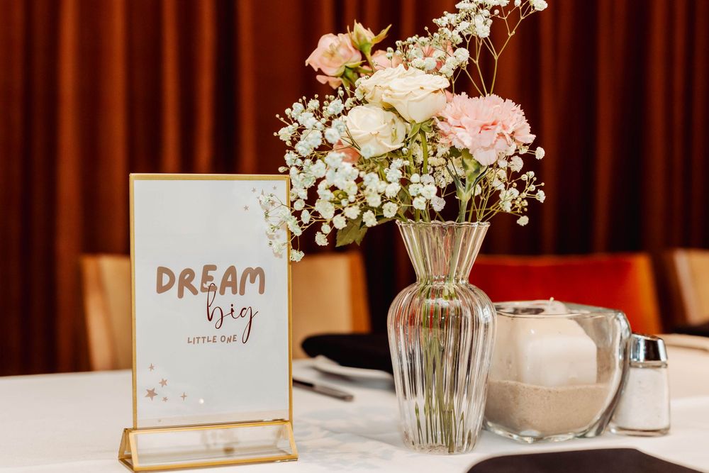 Dream big card with pink and white floral arrangement in glass vase on decorated table.