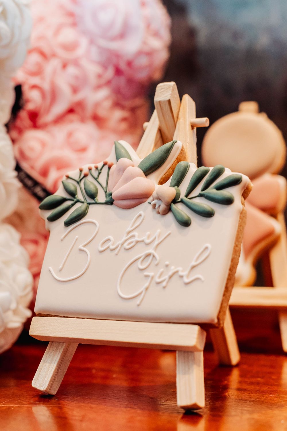 Decorative wooden easel displaying 'Baby Girl' text with pink and green floral accents.