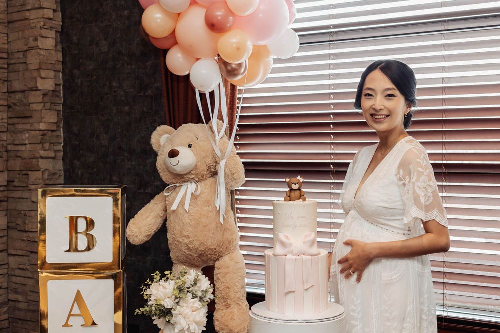 Elegant baby shower display with pink balloons, teddy bear, and wooden letter blocks.