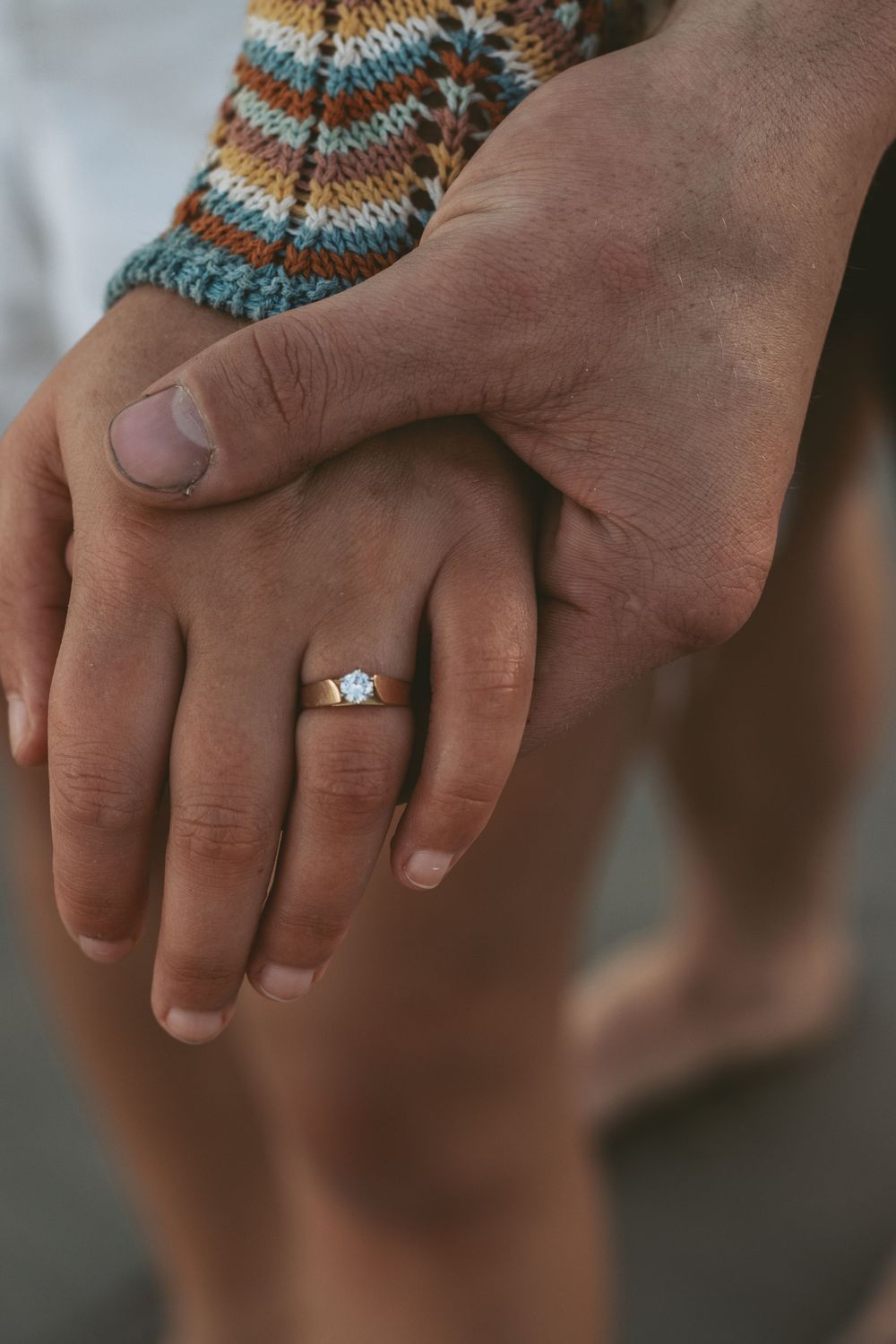 Detailed shot of hands displaying an engagement ring with a solitaire diamond setting.