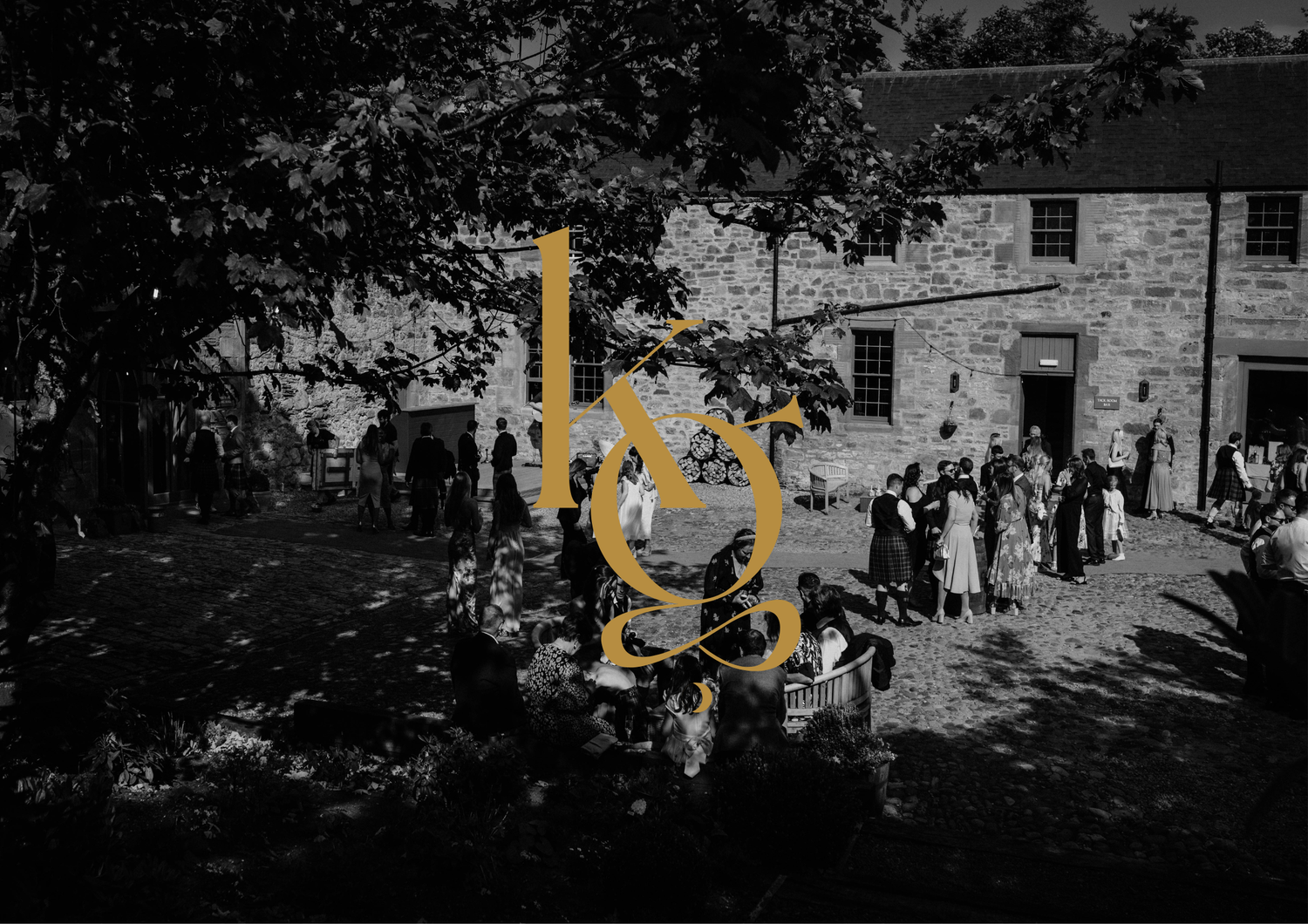 Vintage black and white photo showing guests gathered outside a stone building for a celebration.