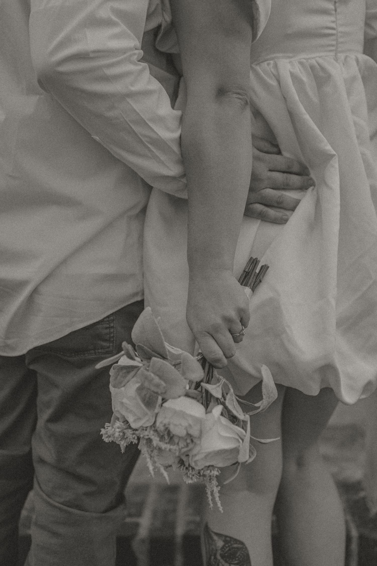 Black and white detail shot by Samantha Campbell imagery of hands holding flowers against formal attire.
