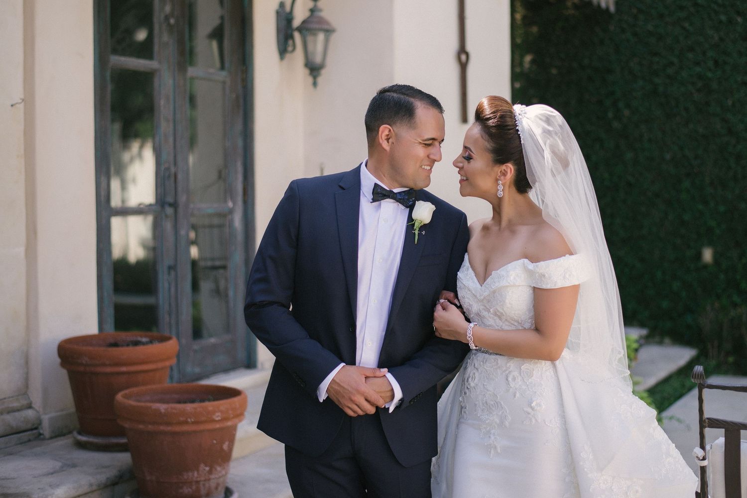 Romantic wedding couple embracing in elegant courtyard setting.