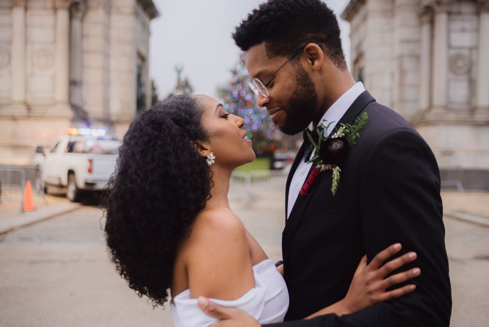 A romantic wedding portrait of newlyweds sharing an intimate moment outside a historic building.