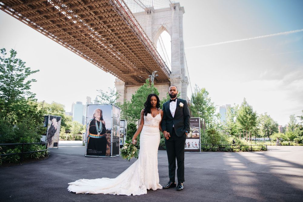 A wedding couple poses beneath the iconic Brooklyn Bridge on their special day.