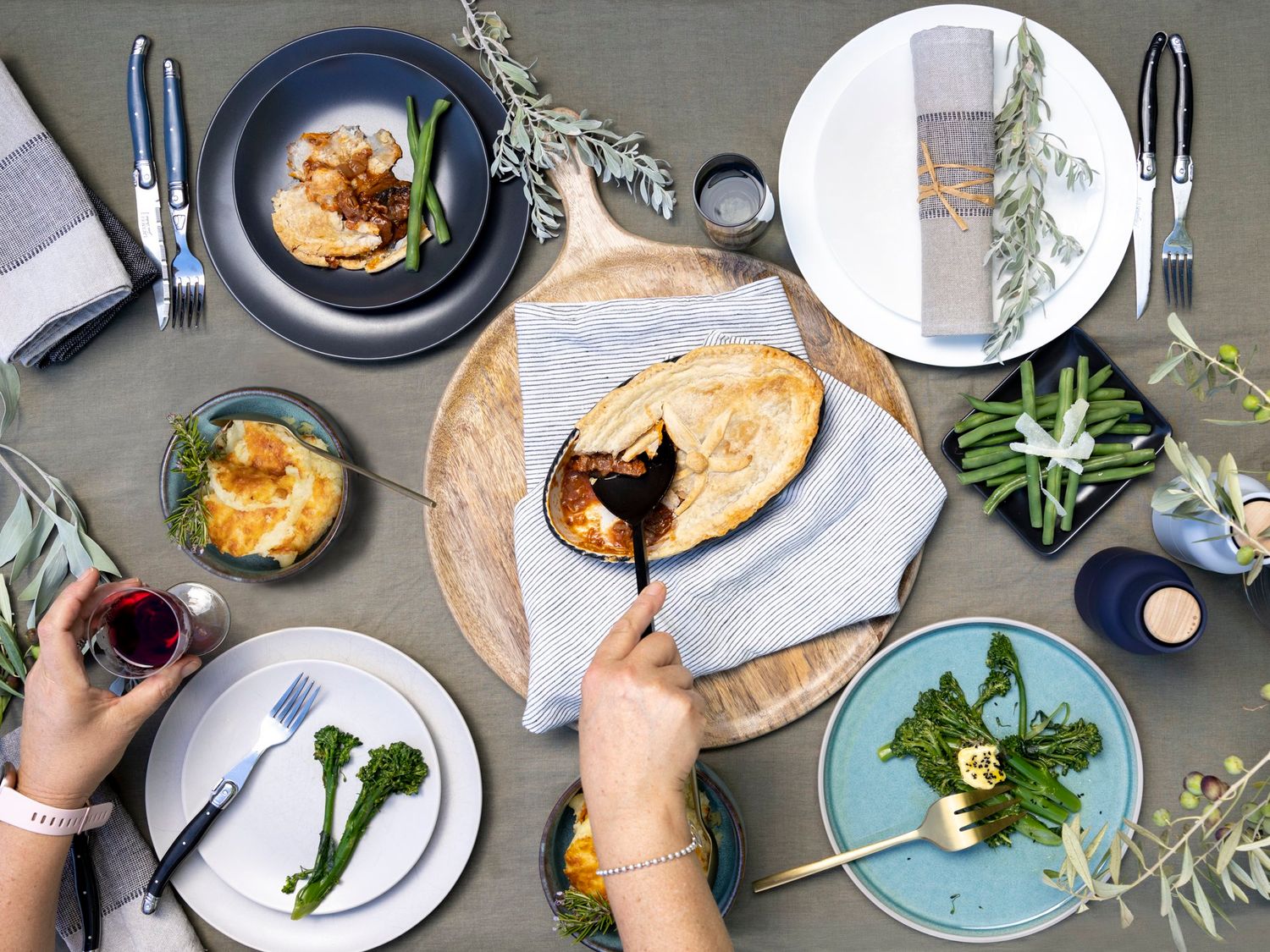 Overhead view of table setting with multiple plates and fresh herbs.