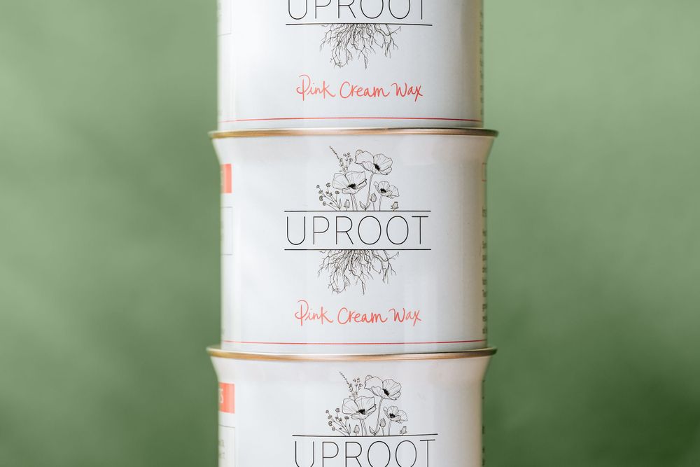 Stack of three white Uproot paint cans against green background.
