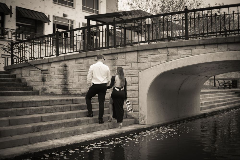 Couple walking along stone steps by a waterway in black and white.