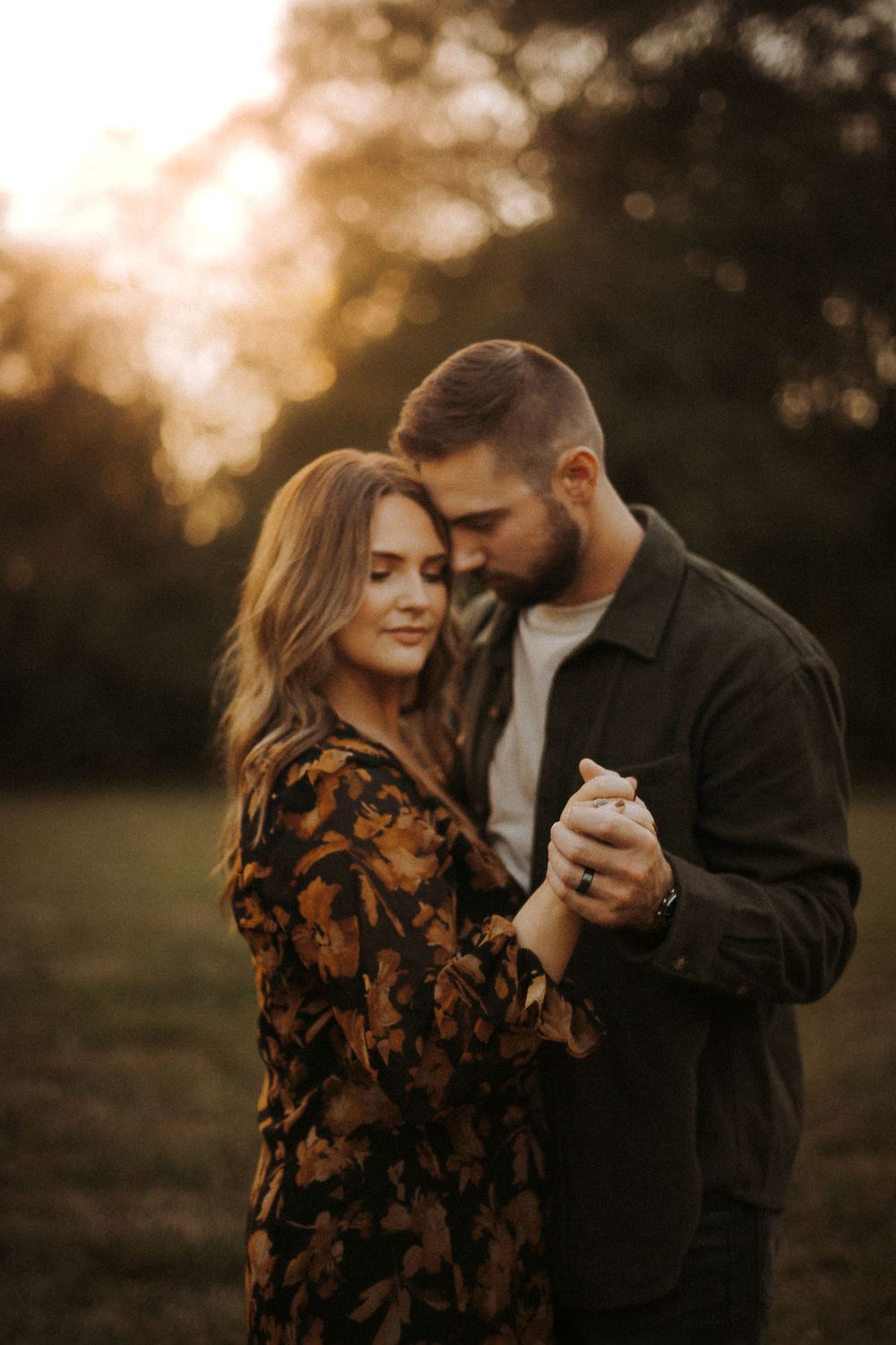 Couple sharing tender moment while dancing outdoors at sunset.