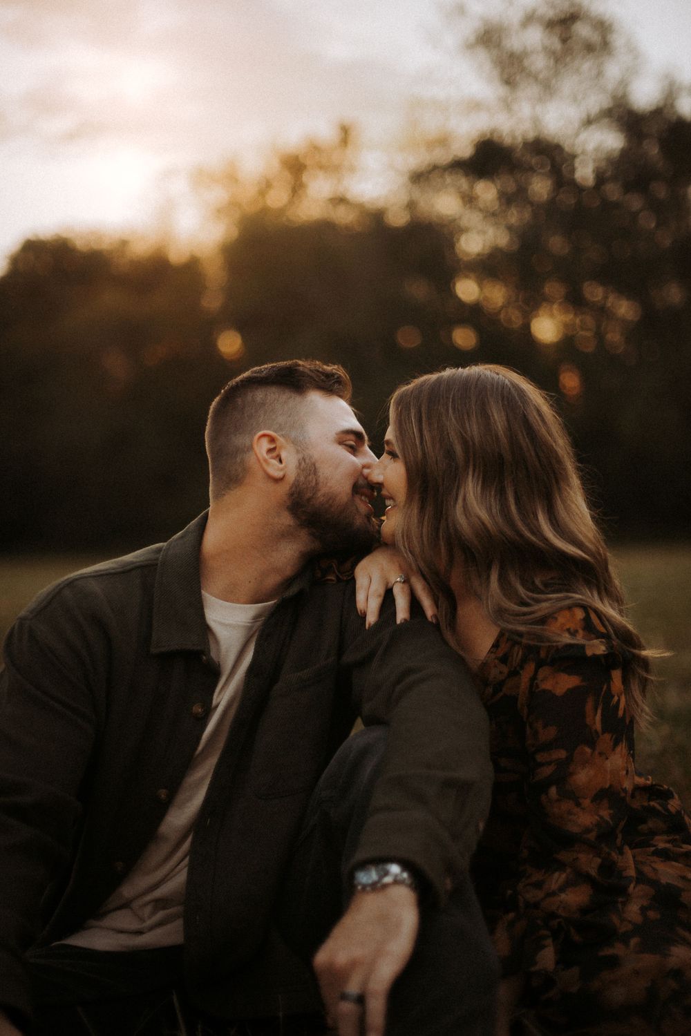 Couple sharing romantic kiss outdoors during golden hour.